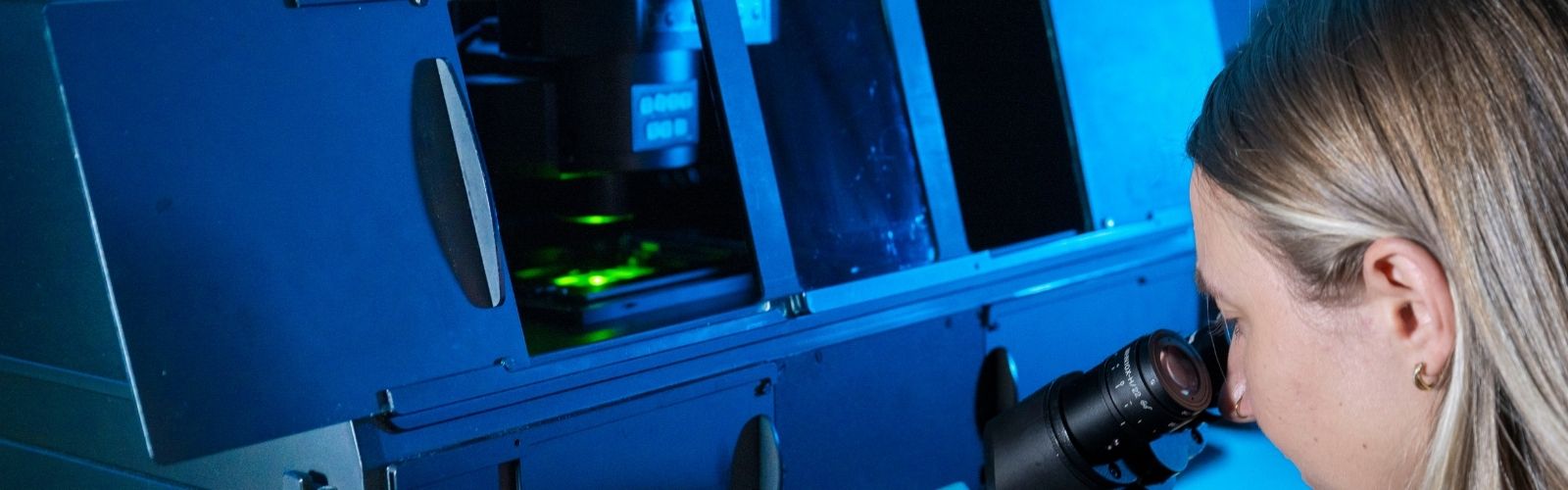 An image of a woman looking through microscope eyepieces