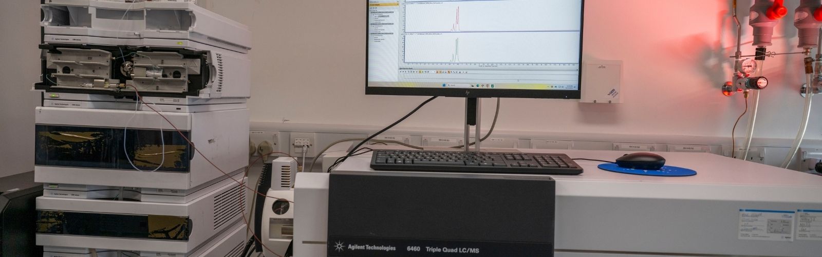 An image of a mass spectrometer and a computer screen displaying graphs