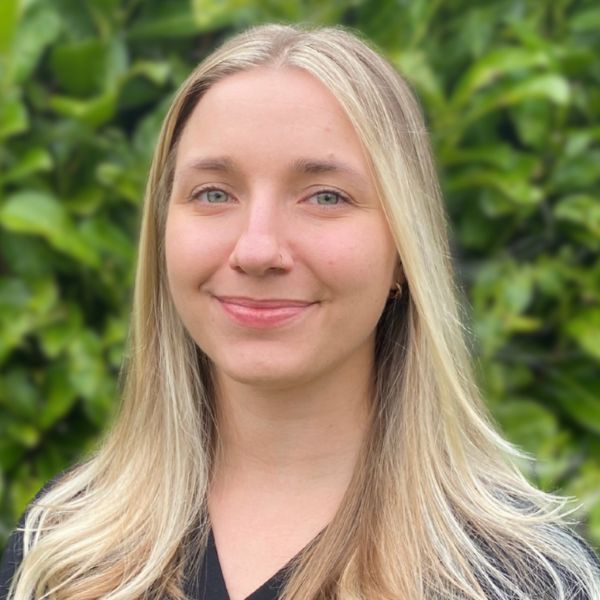 A headshot of Dr. Karolina Salciute, in colour, with green hedges in the background